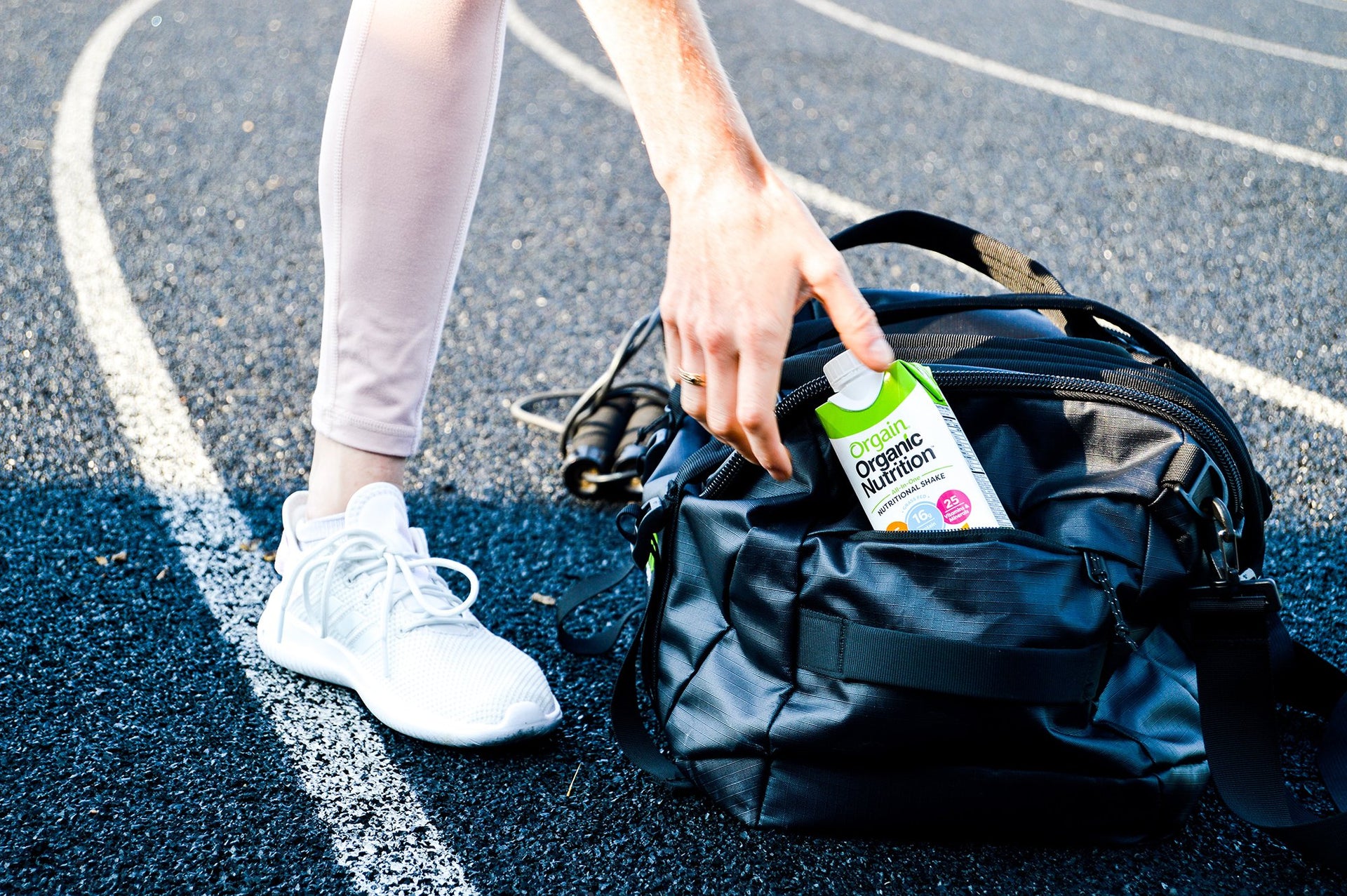 A woman reaching for an Orgain Organic Nutrition shake in her duffle bag