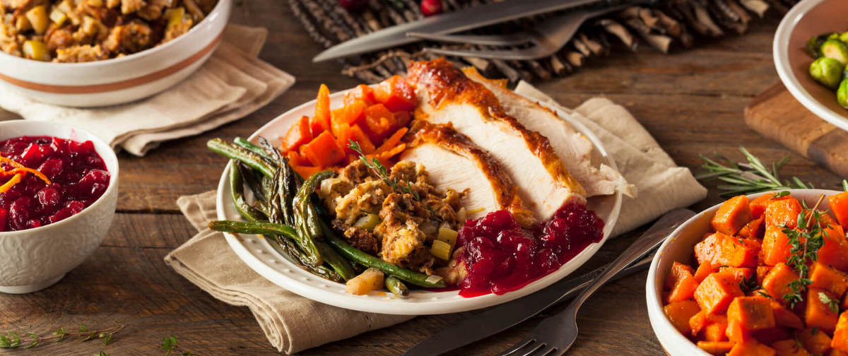 Thanksgiving dinner plate with roasted turkey, green beans, stuffing, candied yams, and cranberry sauce.