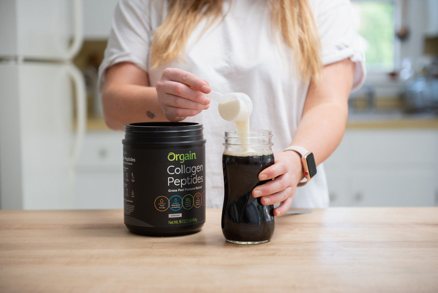collagen peptides being scooped by a woman in her kitchen
