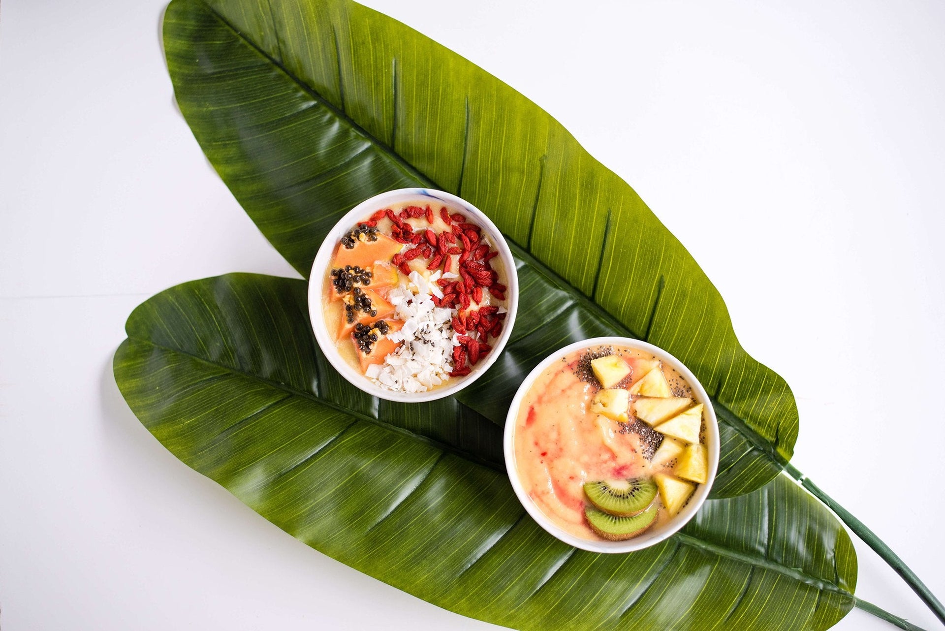 two smoothies on top of large green leaves