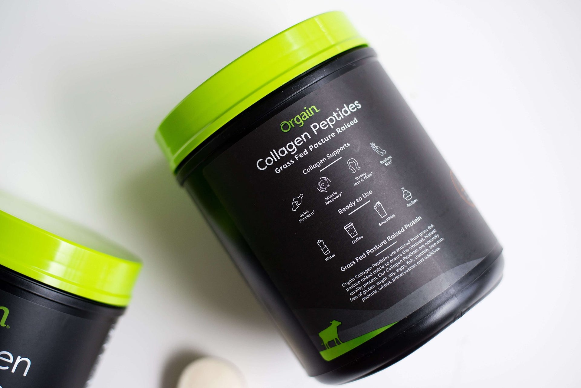 A black and green container of Orgain Collagen Peptides powder lies on its side, with another container partially visible.