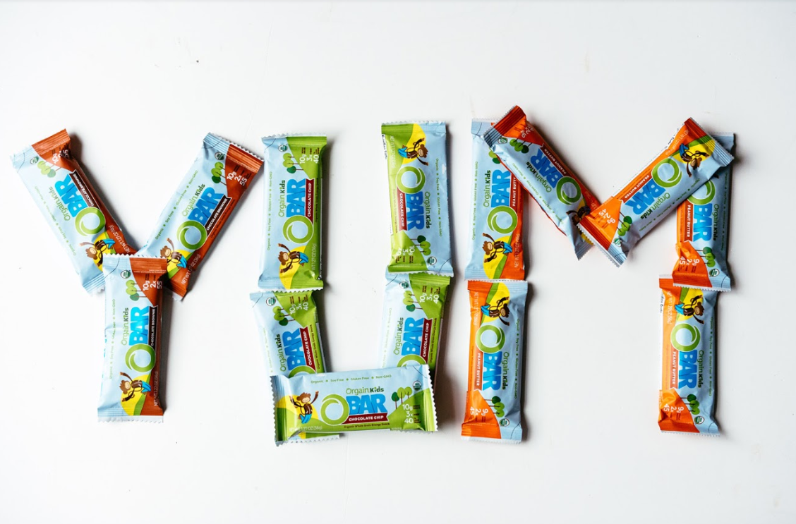 The word "YUM" spelled out with Orgain's Kids' Protein Bars.