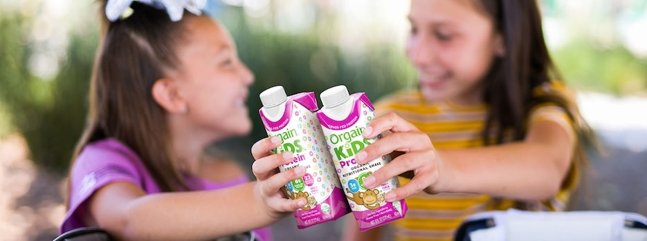two kids holding kids protein organic nutrition shake in fruity cereal flavor