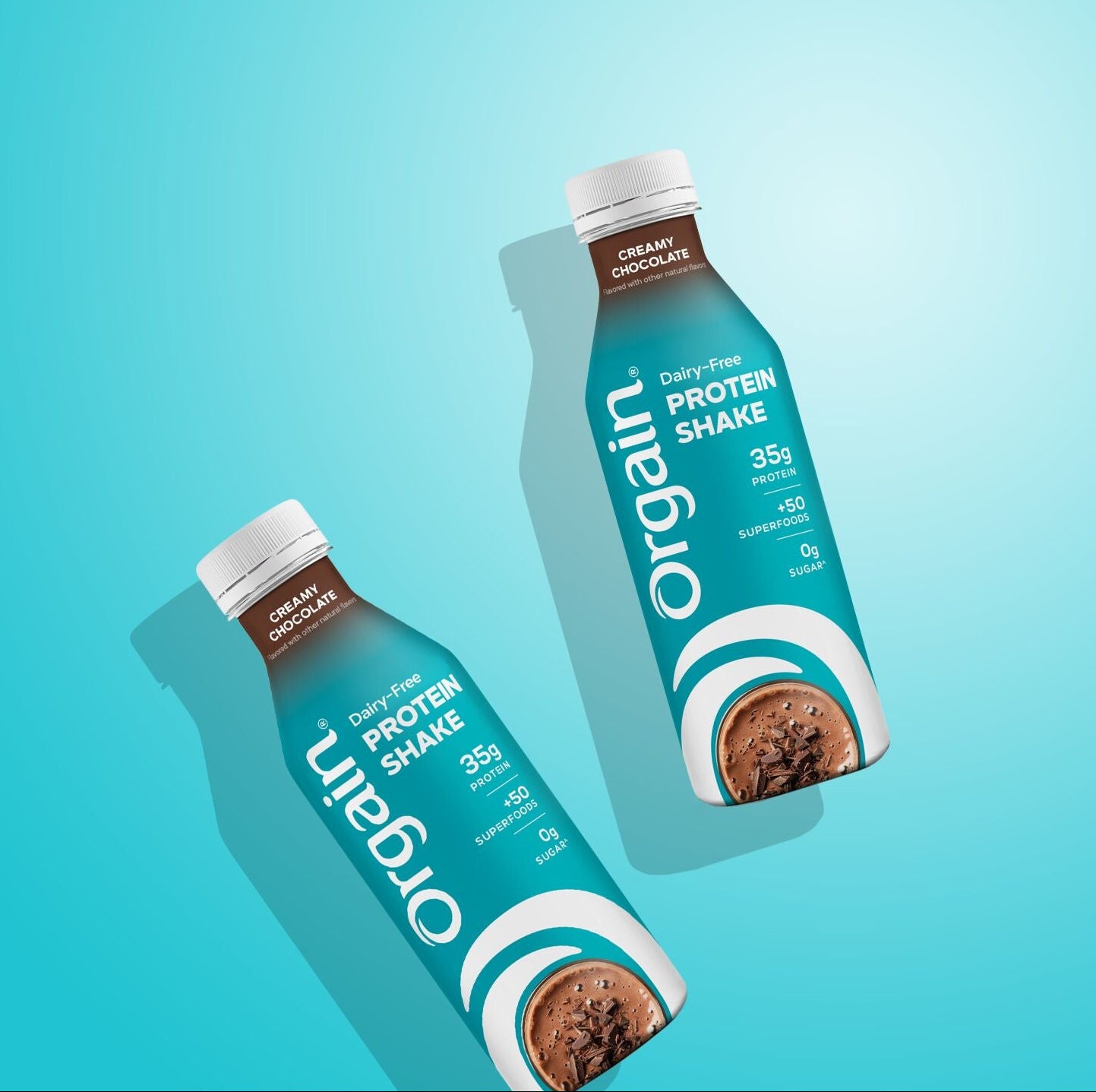 Two bottles of Organ Protein Shake in chocolate flavor, arranged diagonally on a bright cyan gradient background with soft drop shadows.