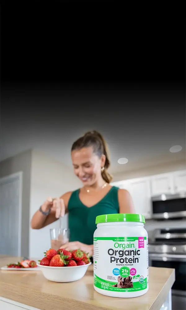 Woman preparing a protein shake with Orgain chocolate protein powder