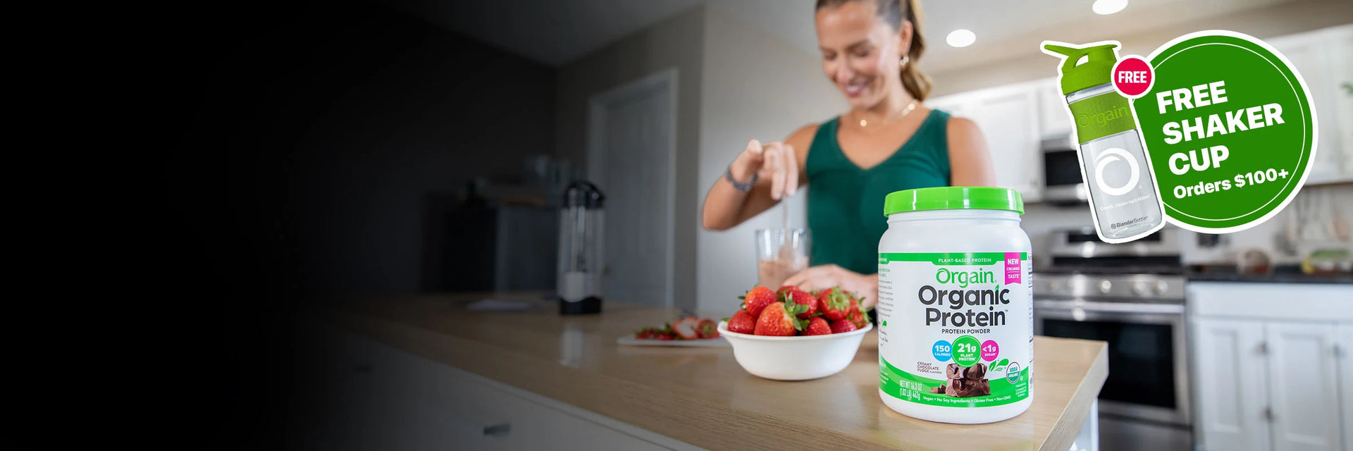 Woman preparing a protein shake with Orgain chocolate protein powder with a callout for Free Shaker Cup on orders $100+