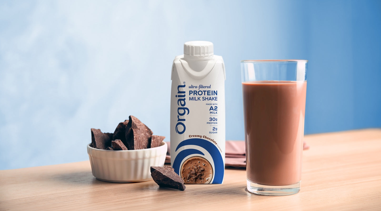 Orgain A2 Protein Shake packaging next to the shake poured in glass cup