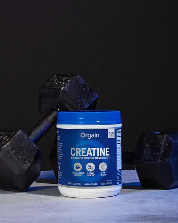 Creatine Powder in front of a few dumbbells