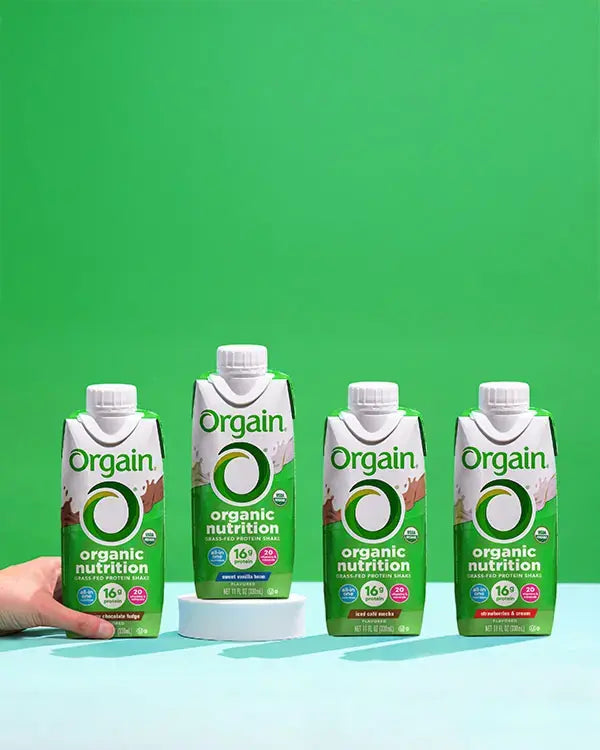 All orgain organic nutrition shakes displayed next to eachother on a white table.