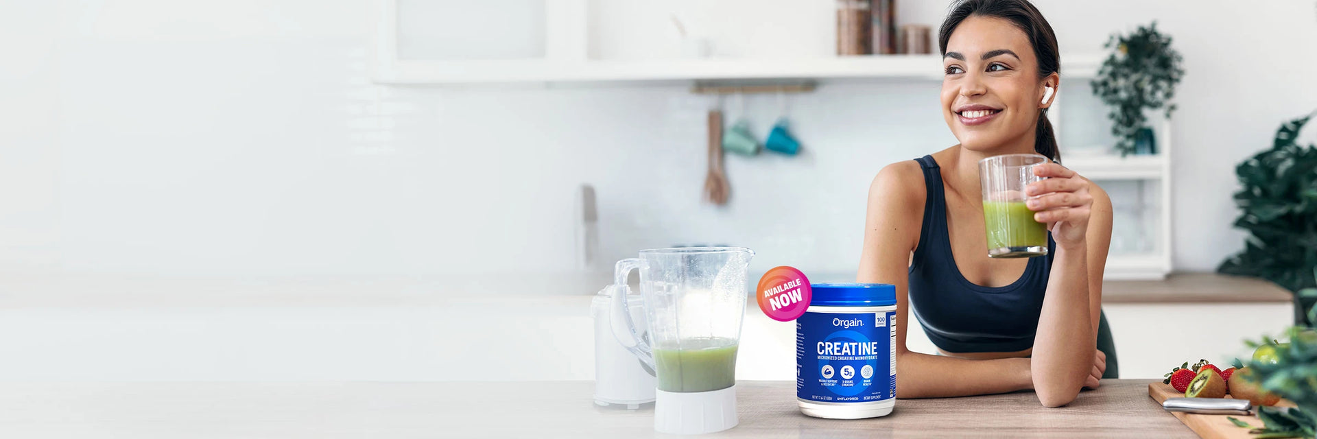 woman drinking a green beverage with Orgain creatine on kitchen counter