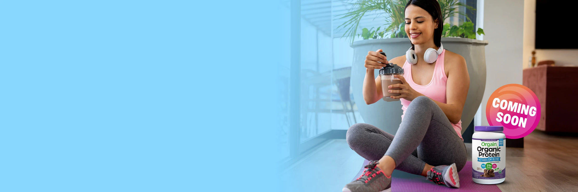 Woman exercising with weights in a home setting, with a 'Coming Soon' Organic Blue bottle visible.
