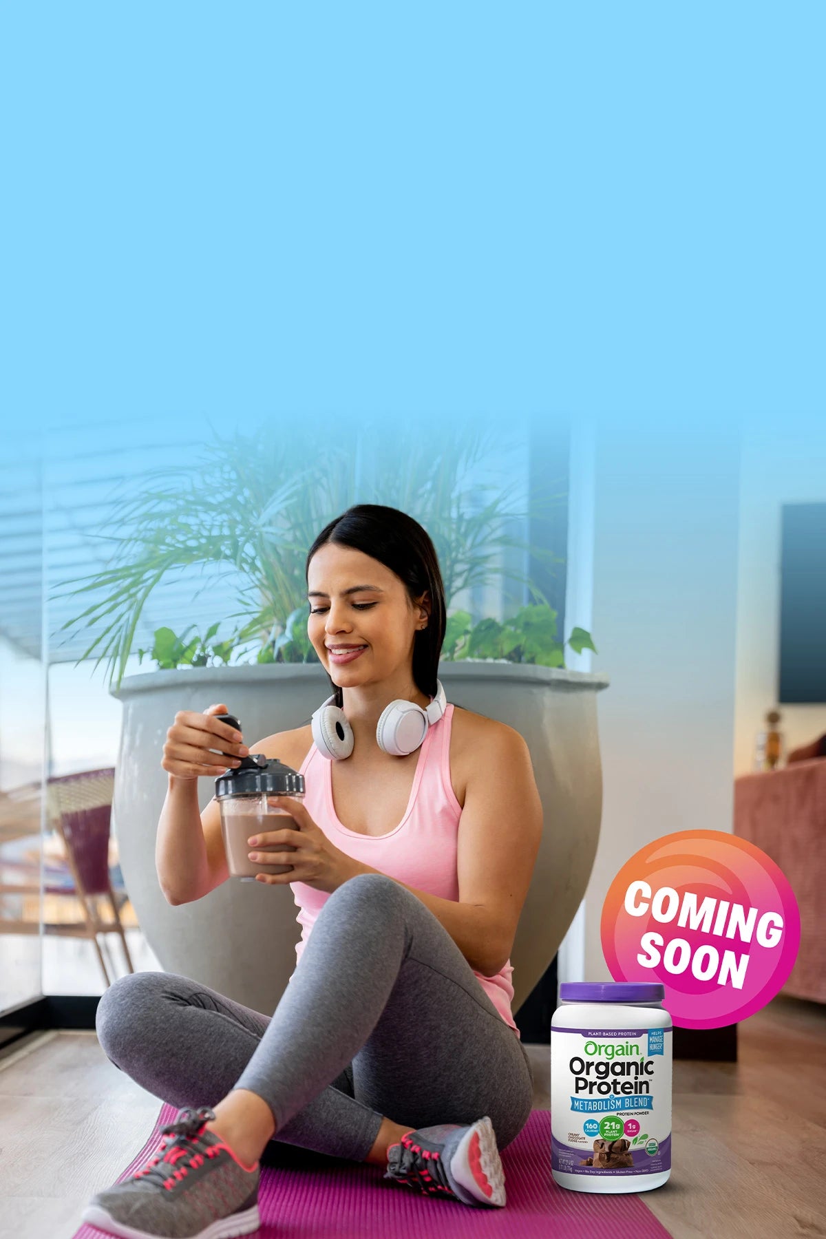 Woman sitting on a yoga mat with a protein supplement and 'Coming Soon' sign in the background